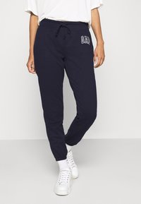 Marina sweatpants med en avslappnad passform, ribbade muddar och en justerbar dragsko vid midjan. Har en vit "GAP" logotyp på vänster lår.