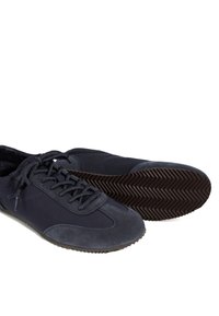 Paire de baskets décontractées bleu foncé à fermeture à lacets et semelles en caoutchouc texturées, une chaussure posée à plat et l'autre sur le côté.