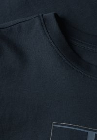 Marineblå bomulds T-shirt med rund hals, der har en glat overflade og pæne syninger. Et subtilt grafisk design er placeret på forsiden.