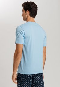 Camiseta azul clara de cuello redondo en suave tejido de algodón, de manga corta, diseño liso, combinada con pantalones cortos marinos estampados con motivos florales.