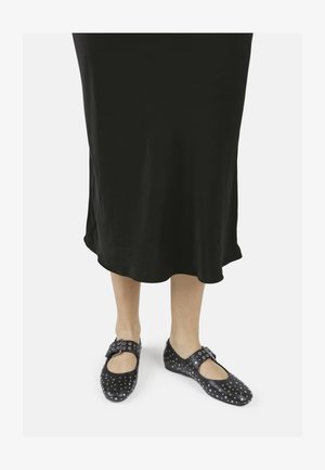 Mustad mustad nahast kingad ümmarguse varbaga, ühe rihmaga ja pandlaga, nupukestega detailid, kantud musta põlvikuni kleidi all.