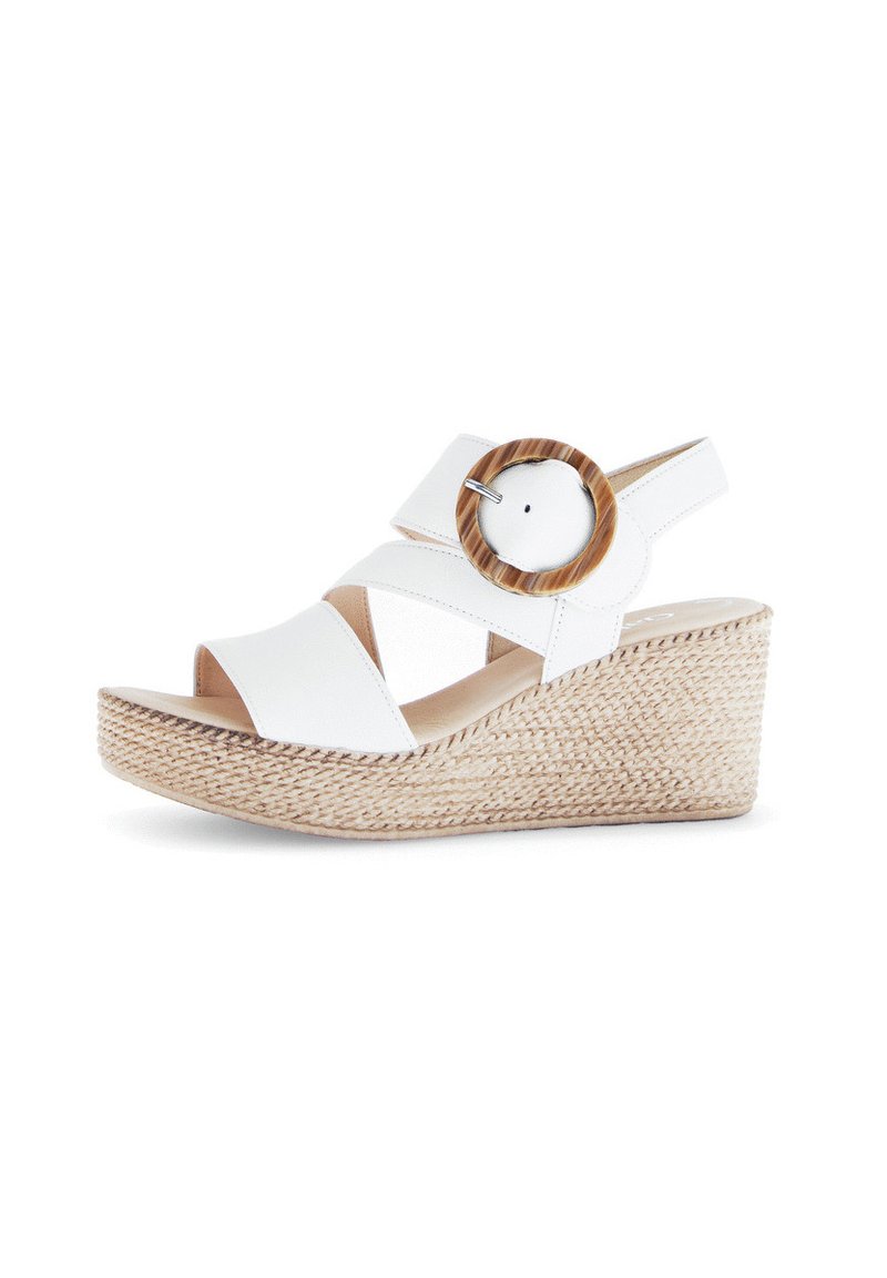 White wedge sandals with crossed straps, large round wooden accent, textured espadrille base, open toe design, and a back strap.