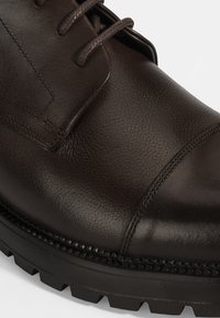 Bruine leren schoen met een gladde afwerking, met een ronde neus, veters en een gestructureerde zool met een gematigd loopprofiel.