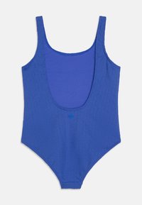 Maillot de bain une pièce bleu avec un col en scoop, en tissu texturé à relief, bretelles larges et un détail à bouton sur le devant. Doublure intérieure lisse.