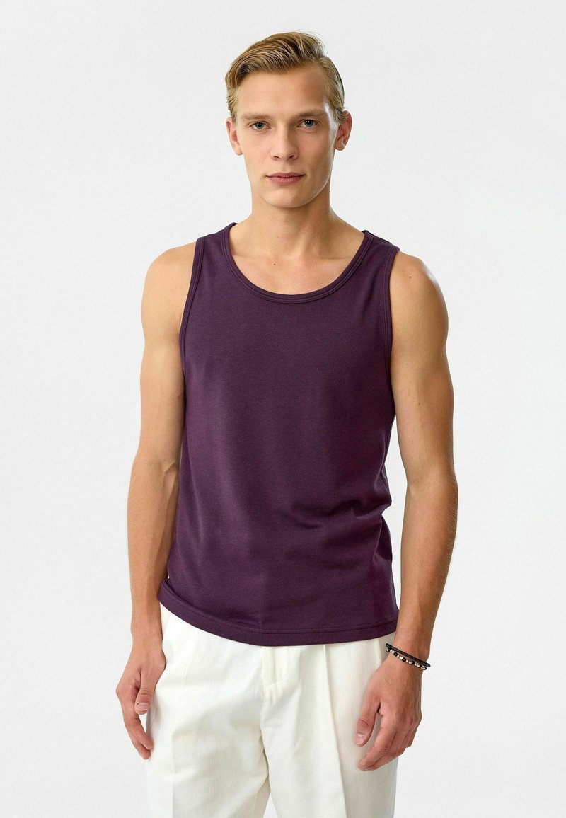 Paarse tanktop van katoen, met een ronde halslijn en mouwloos ontwerp, gecombineerd met lichte broek. Minimalistische stijl.