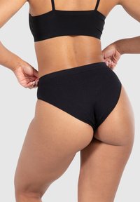 Sous-vêtements noirs côtelés avec taille haute et design sans coutures, présentant une texture lisse et un style minimaliste.