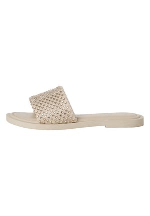 Beige slide sandal med ett brett, nitar strap som har klara rhinestones. Platt sula med en slät yta och minimalistisk design.
