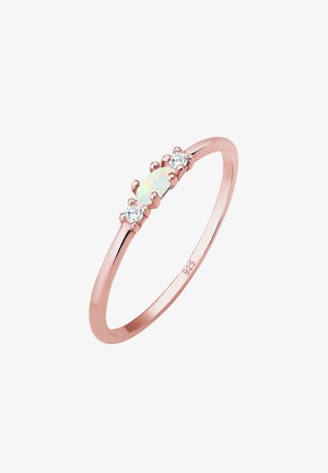 Anillo de oro rosa con una piedra central ovalada de ópalo flanqueada por dos gemas redondas transparentes. Banda suave con un acabado pulido.