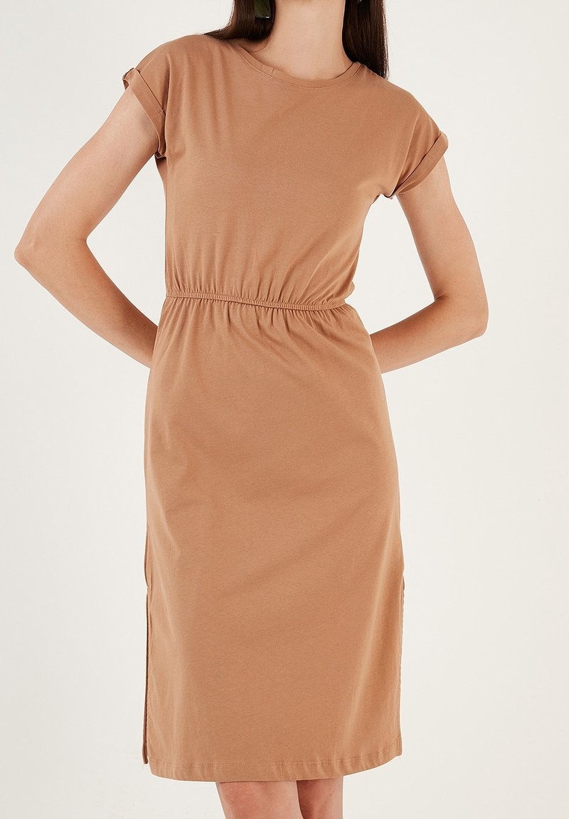 Ruskea, lyhythihainen mekko pehmeästä kankaasta. Ominaisuuksiin kuuluu joustava vyötärö ja sivusaumareikät, jotka tarjoavat rentoa istuvuutta.