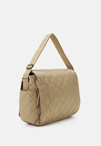 Borsa a tracolla trapuntata beige con forma rettangolare, cinturino regolabile, chiusura con zip e tasca laterale. Texture liscia con motivo a rombi.
