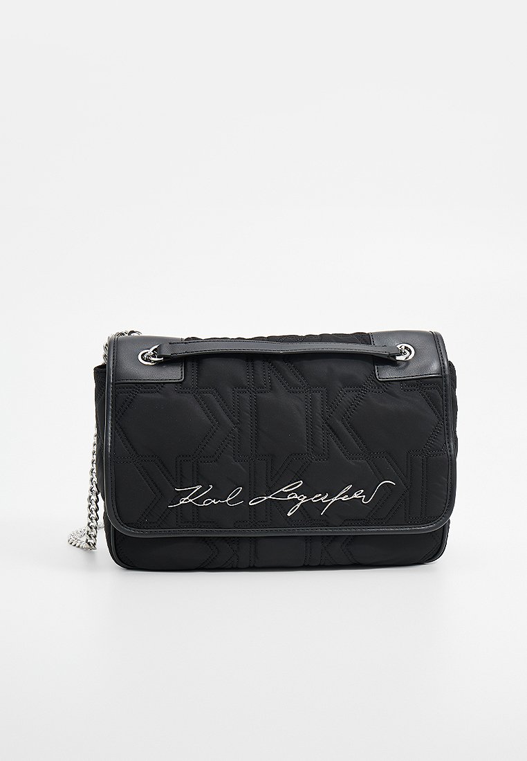 Sac en nylon matelassé noir avec une chaîne en argent, présentant un logo signature en blanc et un motif géométrique sur le devant.