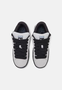 Sneaker in suede grigio con lacci neri a trama, collarino imbottito e suola in gomma nera. Presenta il logo Puma sulla linguetta e una soletta decorata.
