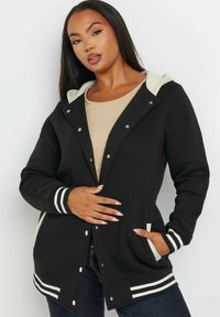 Schwarze Kapuzenjacke mit gestreiften weißen Akzenten, Druckknöpfen und seitlichen Taschen. Weicher Stoff mit glatter Textur.