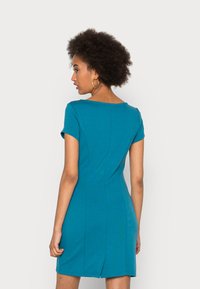 Vestido teal de mangas curtas com silhueta justa, decote quadrado e costuras sutis a correr pela parte de trás. Tecido suave, até ao joelho.