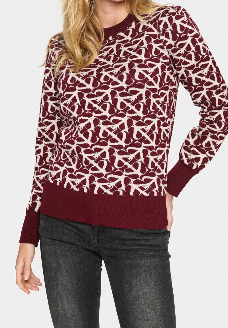 Pull en tricot bordeaux avec un motif abstrait blanc, doté d'un col rond et de poignets et ourlet côtelés. Convient pour une tenue décontractée.