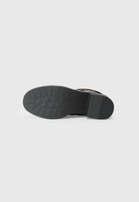 Black rubber sole with a textured surface and tread pattern. Features a cylindrical heel and a flat front for stability.