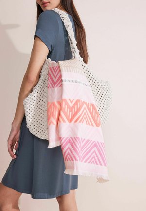 Witte gehaakte tote bag met een textuur, voorzien van een meerkleurige sjaal in roze en oranje tinten, die over de zijkant hangt.