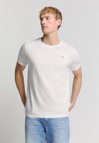 Witte t-shirt met korte mouwen, ronde hals en klein merklogo op de linkerborst. Gemaakt van zachte katoen met een gladde textuur.