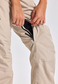 Beige outdoor broeken met een gladde textuur en een ritszak, met versterkte naden en een recht model.