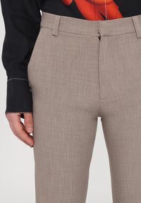 Beige-harmaat housut tekstuurilla, suora malli, vyölenkit ja piilotettu vetoketju.