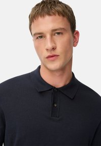 Marineblå polo skjorte lavet af bomuld, med krave, tre-knaps placket og en blød tekstur. Rent design med subtile detaljer.