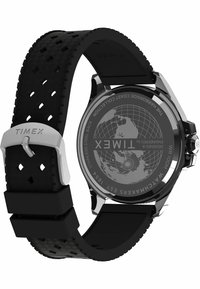 Schwarze Gummiuhr mit strukturiertem Band, Edelstahlverschluss und rundem Gehäuse. Graviertes Globusdesign auf der Rückseite mit Markennamen.