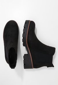 Černé semišové kotníkové boty s elastickými bočními panely, zaoblenou špičkou a masivní gumovou podrážkou s dřevěným akcentem. Texturovaný povrch a elegantní design.