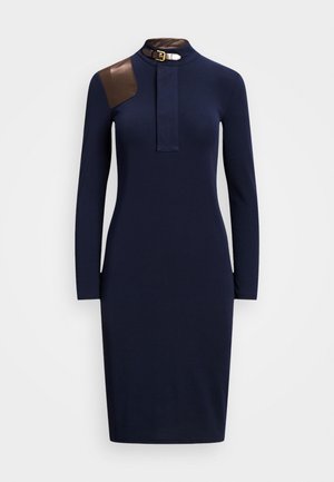 Robe ajustée à manches longues bleu marine avec col montant, présentant un patch d'épaule en cuir marron et un détail boucle.