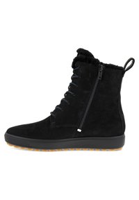 Stivale alla caviglia in suede nero con lacci frontali, cerniera laterale, colletto in morbido pelliccia artificiale e suola in gomma testurizzata con un battistrada in contrasto color tan.