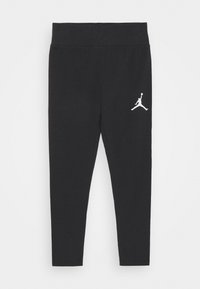 Czarne legginsy wykonane z elastycznej tkaniny z szerokim pasem w talii. Posiadają białe logo Jumpman na dolnej części lewej nogawki.