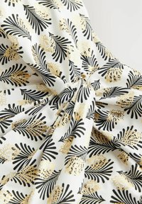 Witte stof met zwart en gouden bloemenpatroon. Gladde textuur met een lichte glans, featuring in elkaar vervlochten bladeren en bloemen.