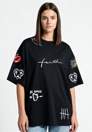 Jeune femme portant un T-shirt noir oversize avec les textes blancs « faith », « Mi Amor », des lèvres rouges, des cœurs qui pleurent, le soleil, la lune et des marques de comptage, debout.