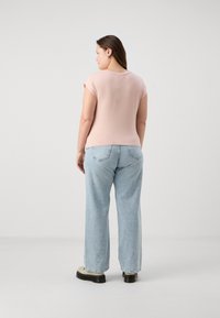 Ροζ fitted t-shirt με κοντά ρολωμένα μανίκια, σε συνδυασμό με ελαφριά μπλε τζιν παντελόνια σε φαρδιά γραμμή και chunky παπούτσια με μαύρη σόλα.