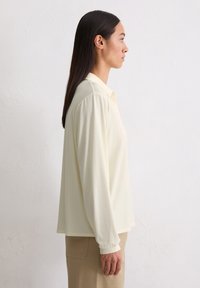Lichtgeel blouse met lange mouwen en een kraag, in een ontspannen pasvorm en van een zachte stof. Heeft een rechte zoom en subtiele elastische manchetten.