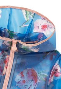 Transparent blå regnjacka med blommönster. Har en rosa dragkedja och matchande bibs runt kragen. Slät, blank plastmaterial.