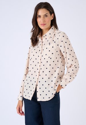 Camicetta rosa chiaro con bottoni e pois blu scuro. Presenta un colletto, maniche lunghe e una tasca sul petto. Tessuto liscio con una vestibilità comoda.