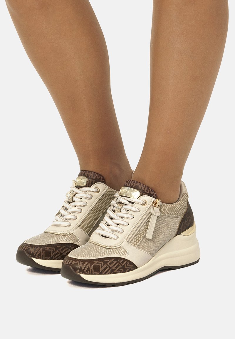 Sneakers con un mix di materiale beige metallico testurizzato e accenti marrone scuro. Design con lacci e dettaglio zip, sole con motivo.