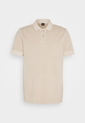 Μπεζ πόλο μπλούζα φτιαγμένη από απαλό βαμβάκι. Διαθέτει κλασικό γιακά, δύο κουμπιά και ένα μικρό κεντημένο λογότυπο στο στήθος.