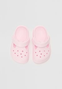 Vaaleanpunaiset muovikengät, joissa on sileä pinta, avoin takapuoli ja ilmanvaihtoaukot. Varustettu jalkapöydän yli kulkevalla nauhalla tukevan istuvuuden saavuttamiseksi.