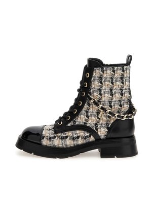 Bottine noire en cuir verni et tweed avec un laçage à l’avant, œillets dorés, semelle épaisse et détail décoratif d’une chaîne dorée sur le côté.