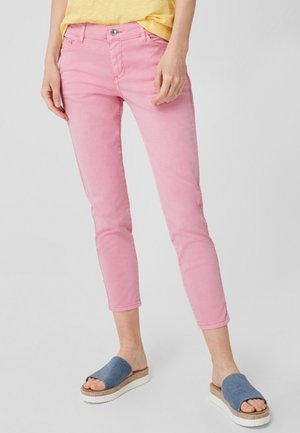 Lichtroze denim skinny jeans met een medium hoge taille, een vijf-pocket ontwerp en een subtiele textuur; gecombineerd met blauwe slide sandalen.