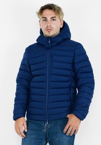 Giacca in piuma navy con design a trapunta orizzontale, chiusura frontale con zip, colletto alto e cappuccio regolabile. Presenta una piccola tasca sul petto.
