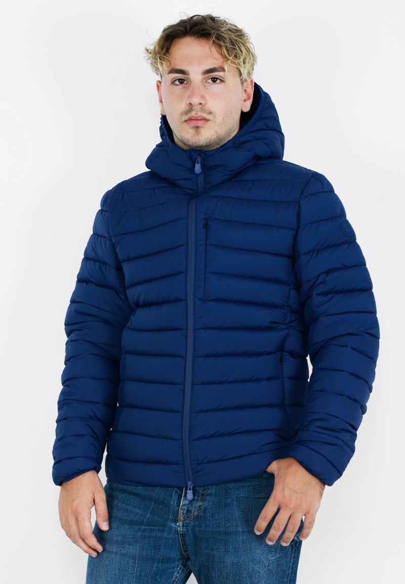 Giacca in piuma navy con design a trapunta orizzontale, chiusura frontale con zip, colletto alto e cappuccio regolabile. Presenta una piccola tasca sul petto.