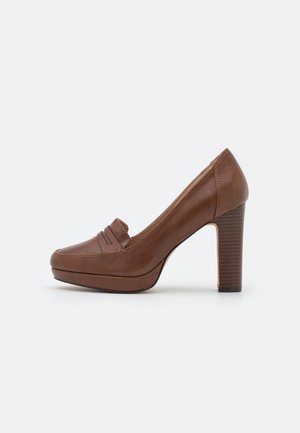 Brauner Lederloafer mit hohem Blockabsatz und einem Pennyriemen vorne.