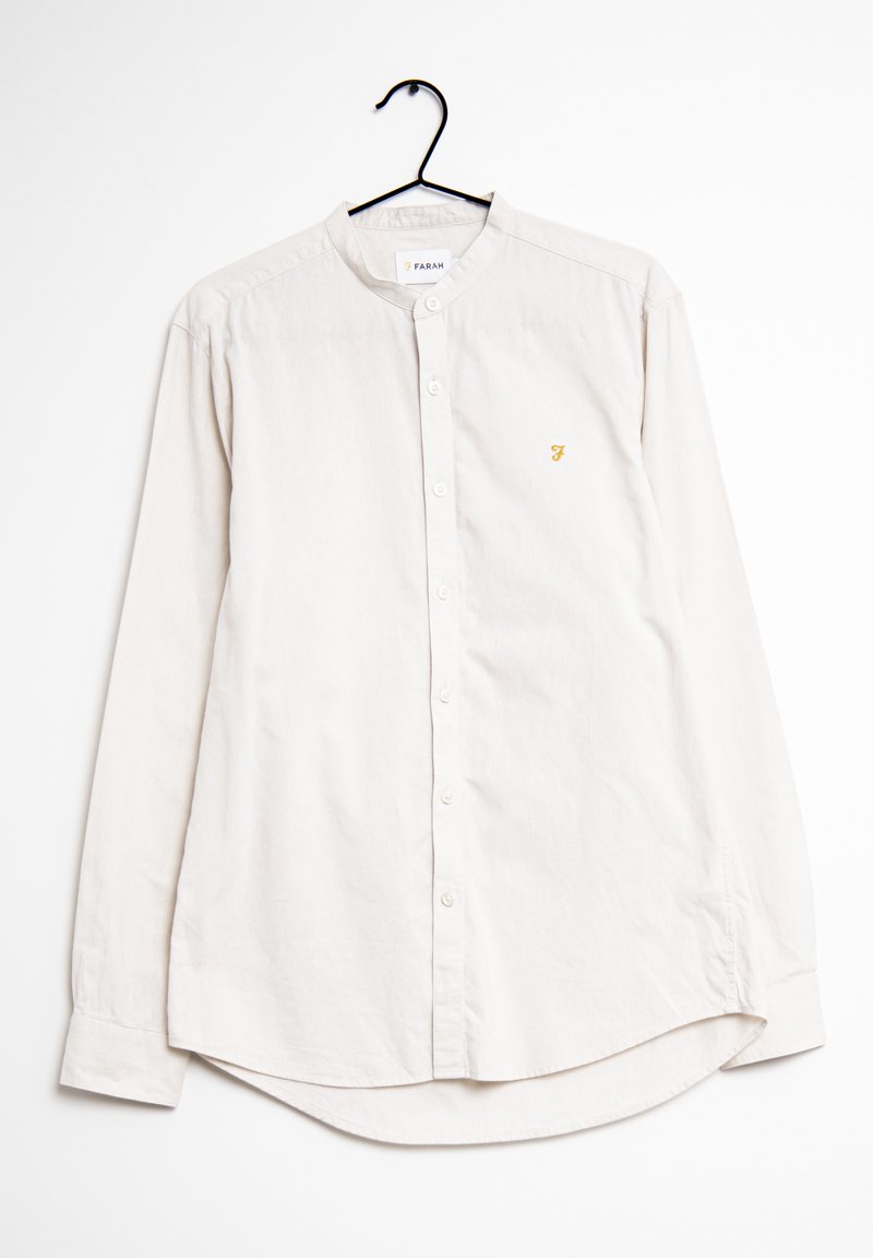 Camicia a maniche lunghe beige chiaro con colletto a banda, bottoni frontali e un piccolo logo dorato sul lato sinistro del petto. Tessuto di cotone liscio.