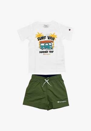 T-shirt bianca con la scritta "Surf Van Summer Trip" e grafica di un furgone con palme, abbinata a pantaloncini verde oliva con coulisse e logo Champion.