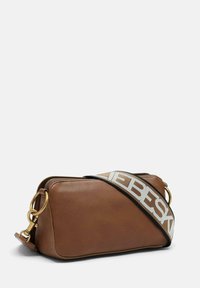 Borsa a tracolla in pelle marrone con chiusura zip, hardware dorato e una tracolla bianca con lettering nero. Forma rettangolare e texture liscia.