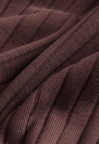 Tejido marrón acanalado que muestra un patrón texturizado con líneas diagonales. El material parece suave y tejido, resaltando su profundidad y detalle.