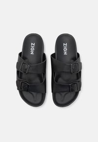 Svarta sandaler med två justerbara remmar och fyrkantiga spännen, tillverkade av smidigt material och med en konturerad sula för komfort.