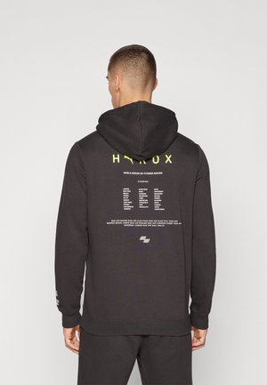 Schwarzer Kapuzenpullover mit gelber Schrift und Grafiken auf dem Rücken, aus Baumwollmaterial und mit gerippten Bündchen und Saum. Kein vorderes Design sichtbar.